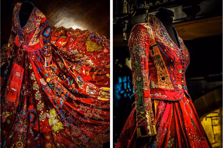 Two detailed views of The Red Dress from The Red Dress Project, showcased at Oakwell Hall during the WOVEN in Kirklees Festival. The dress features intricate hand embroidery in vibrant colors, symbolizing global collaboration and storytelling—highlighting the craftsmanship discussed in this Red Dress Exhibition Review.