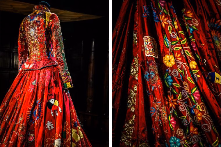 Rear and side views of The Red Dress at Oakwell Hall, captured for this Red Dress Exhibition Review during the WOVEN in Kirklees Festival. The hand-embroidered panels feature vivid floral patterns, peace symbols, and cultural motifs that highlight the collaborative artistry behind The Red Dress Project Review.