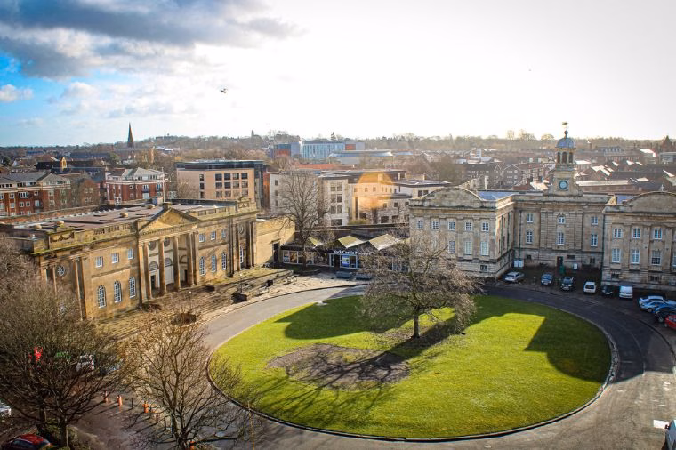 Elevated view of York Castle Museum surrounding the circular lawn of the Eye of York, with its historic Georgian buildings beneath a bright winter sky.