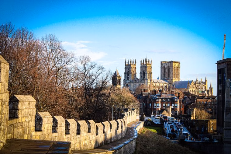 View along York’s medieval city walls towards York Minster, with its Gothic towers rising above the rooftops on a clear winter day.